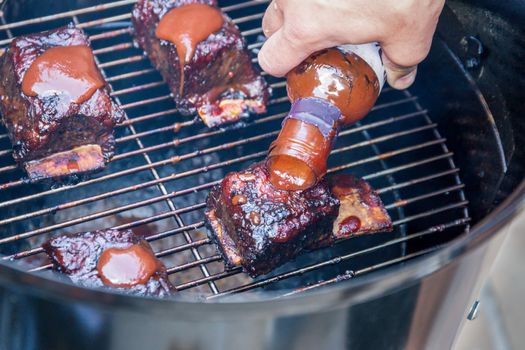 Cooking marinated beef short ribs on an outdoor barbecue