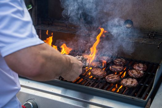 Marinated lamb joint and beef burgers cooking on a barbecue