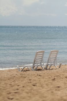 Deck chair in the sand on the shore. Relax, relaxation on the beach. Blue water in the ocean sea. Travel to the sea of the island. Holidays at sea. Air tourism. High quality photo