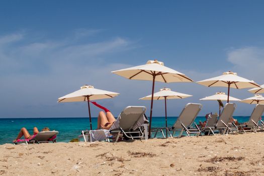 Tourists relaxing on sunlounger on the beach on Lefkada island, Greece