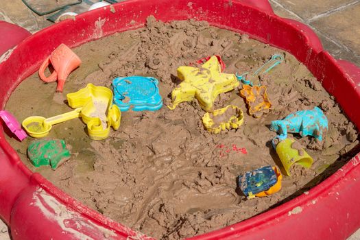 An untidy and unhealthy sandpit, waterlogged with mould