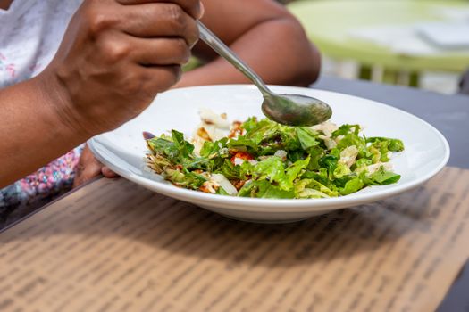 A young woman eating a fresh salad in the sunshine