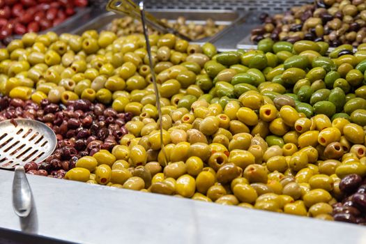 Bowls of green and black olives on display on a stall