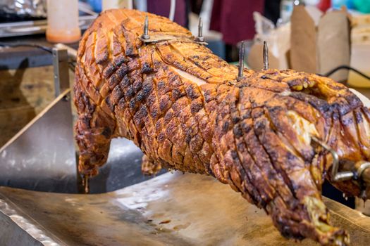 A spit roasted pig on a market stall