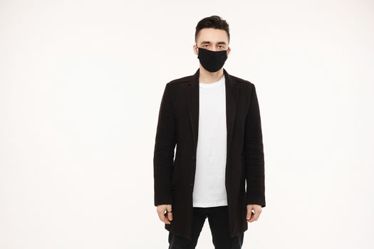 Handsome young man in black protective mask isolated on white background. Healthy lifestyle concept. Seasonal illness, and seasonal flu concept. Men wearing medical mask to prevent infection, airborne respiratory illness such as flu, 2019-nCoV.