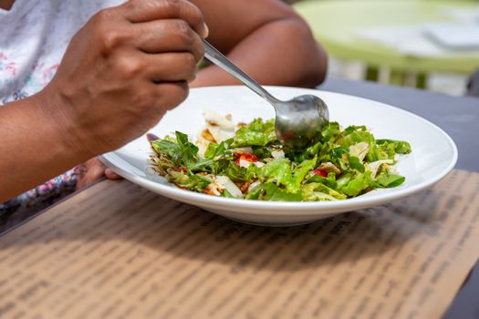 A young woman eating a fresh salad in the sunshine