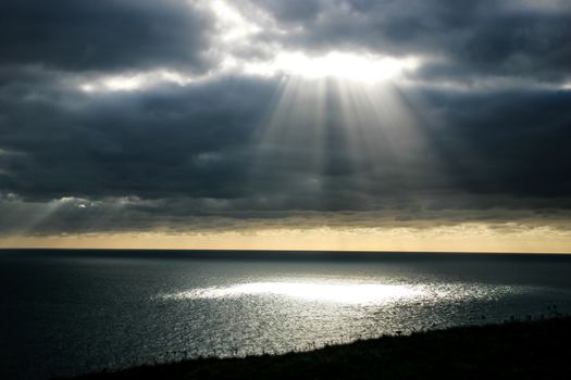 A shaft of light breaking through the dark clouds.  Provides imagery of hope, faith, religion