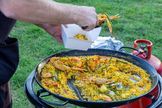 A large pan of seafood paella being served outdoors