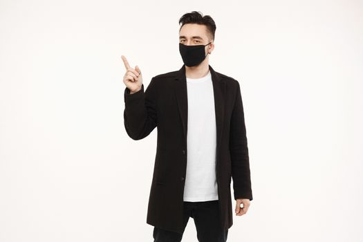 Handsome men in black protective mask pointing finger to the left and up, isolated on the white background with copy space. Lifestyle protective against viruses, seasonal illness and air pollution. Healthcare concept.