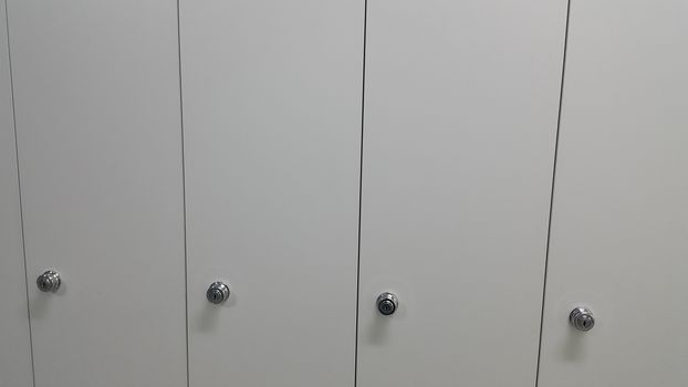 Perspective view of lockers or cupboards in a row with white doors, keys and locks