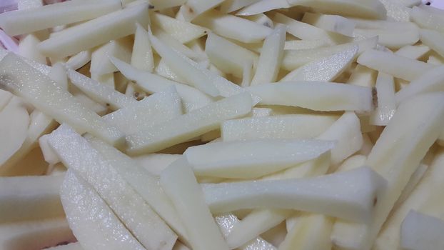 Closeup view of uncooked potato french fries or potato sticks with copy space for text