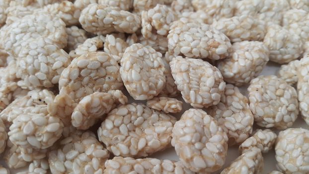 Closeup view of home made Asian sweet food called rewri or rewdi oe sesame seed sweet mad with jaggey and served in a white plate. 