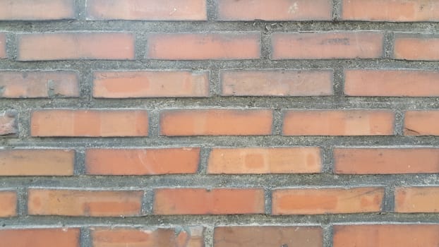 Closeup texture of red brick wall. A background of a weathered old exterior brick wall in the sunshine.