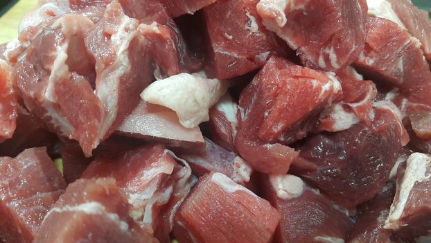 Close up view of fresh finely chopped meat cubes. Red meat small steaks with whitish meat fat.