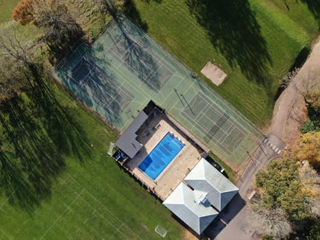 Aerial view of three tennis courts and and an open air swimming pool