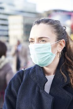 Young woman wearing face mask while walking in the streets of London