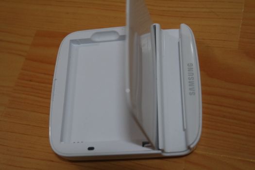 White colored battery charging box for electronic devices like mobile phone. Potable charging box is placed on a wooden floor.