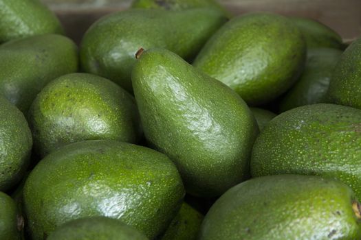 A close up of avocados on display on a market  stall