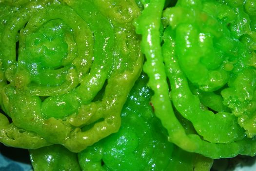 Crispy sweet Asian dessert green Jalebi cooked and served in Festival, Indian sweet street food with juicy syrup, a closeup view.