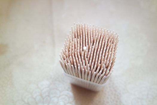 High angle top view of wood needles or wooden tooth picks arranged in a white plastic box container