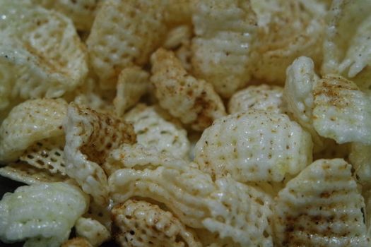 Closeup view of freshly fried chips as fast food for tea break. Potato chips with spices sprinkled on it. Fast food background for advertisements.