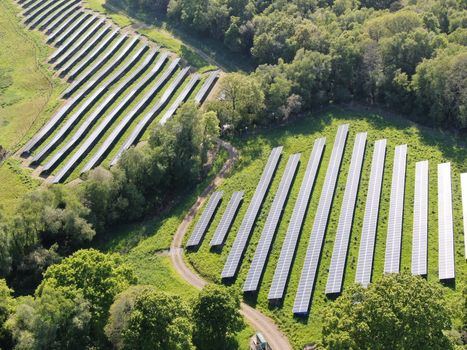 an aerial shot showing rows of solar panels catching the sun and generating electricity in a rural environment