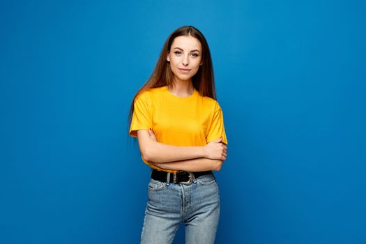 Front view of a model girl with slim body in oversized yellow t-shirt and jeans at the blue background, isolated.