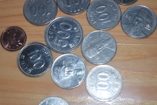 Silver shining Korean won coin scattered over a wooden floor.