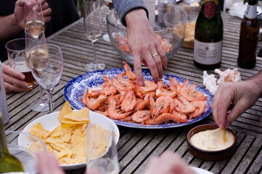 Friends aharing a plate of prawns at a social gathering