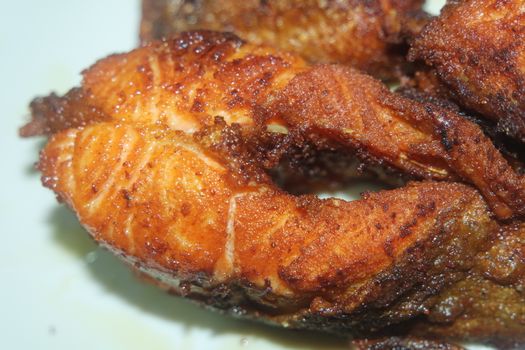 Spicy and crunchy barbecue of fried fish fillet on a white background. Homemade grilled trout fish steaks for health nourishments.