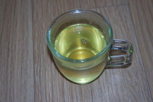 Glass cup having brewed fragrant green tea or qehwa or qahwa on the wooden floor. It is served with sugar or honey and nuts