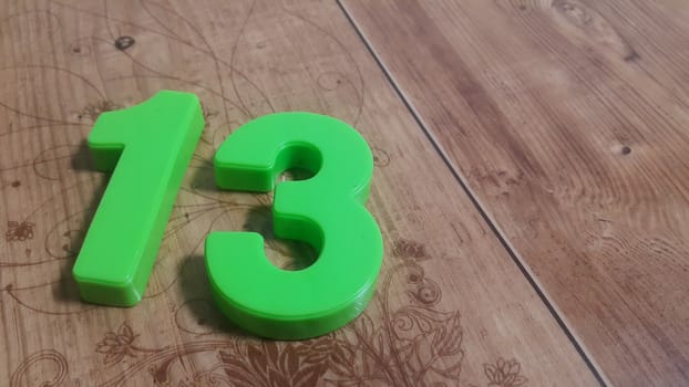 Plastic colored alphabets making words are placed on a wooden floor. These plastic letters can be used for teaching kids.