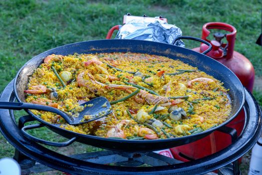 A large pan of seafood paella being served outdoors