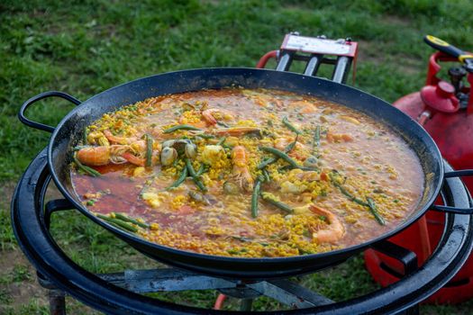 A large pan of seafood paella being prepared outdoors