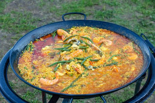 A large pan of seafood paella being prepared outdoors
