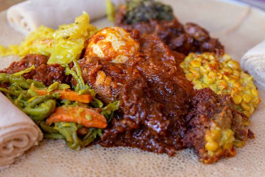 Injera served with Chicken and egg Doro Wat, berbere, vegetables and lentils.  Injera, the national dish of Ethiopia, is a sourdough flatbread made from teff flour.