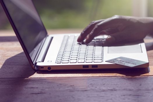 A black man conducting an online transaction with laptop and credit card