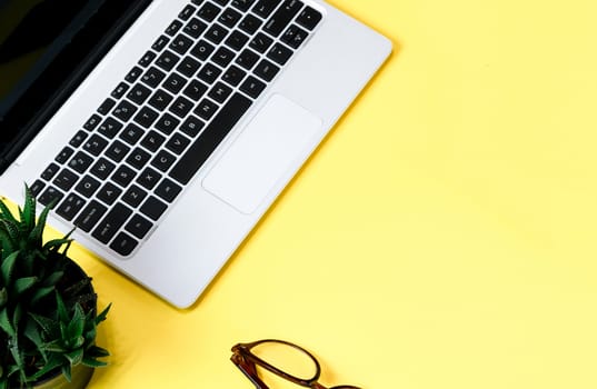 Laptop placed on a yellow table background of business working place with cup coffee, Empty workspace