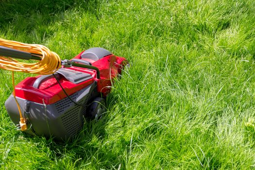 A lawnmower on a lawn of long grass in need of cutting