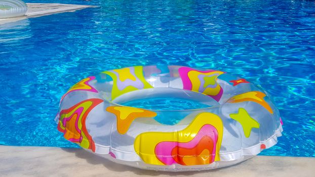 Vibrant rubber ring floating on the blue water of a swimming pool in the summer sunlight