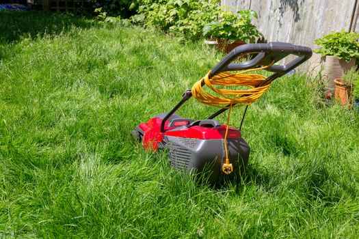 A lawnmower on a lawn of long grass in need of cutting