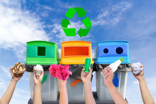 Hand holding garbage recycling bins on sky background