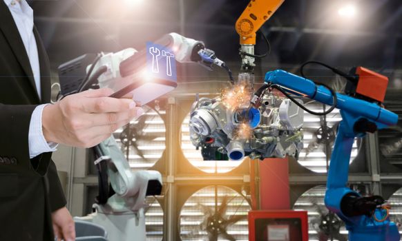 System engineer with smartphone control automation robot arms the production of factory parts engine manufacturing industry robots and mechanical arm