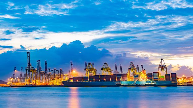 Freighter ship loading cargo at loading dock on twilight time. Singapore, south east asia.