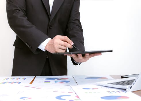 Businessmen holding tablets, analyzing graphs on desks, white background.