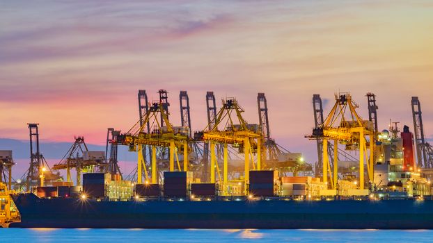 Freighter ship loading cargo at loading dock on twilight time. Singapore, south east asia.