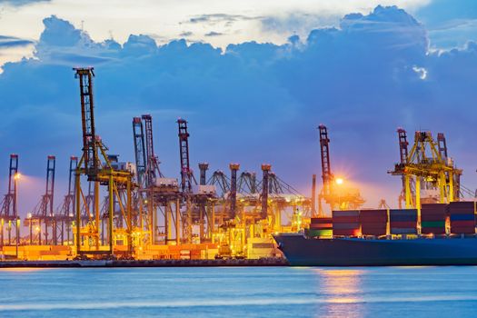 Freighter ship loading cargo at loading dock on twilight time. Singapore, south east asia.