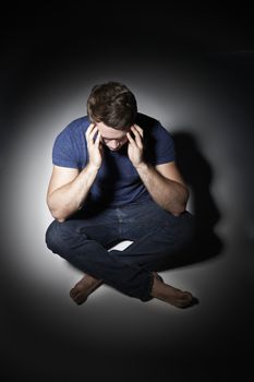 Unhappy Young Man Sitting In Pool Of Light