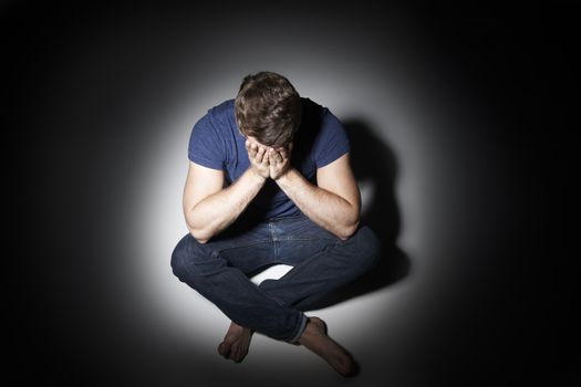 Unhappy Young Man Sitting In Pool Of Light