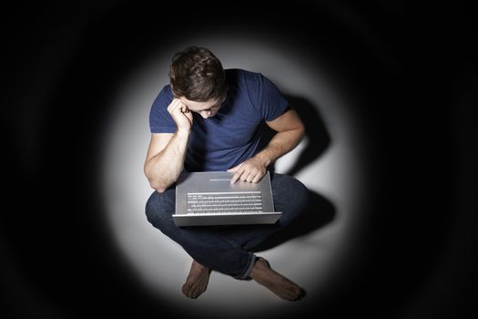 Young Man Using Laptop In Pool Of Light